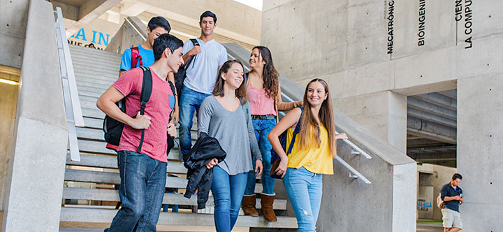 Tres estudiantes celebran con entusiasmo en las escaleras de la univ