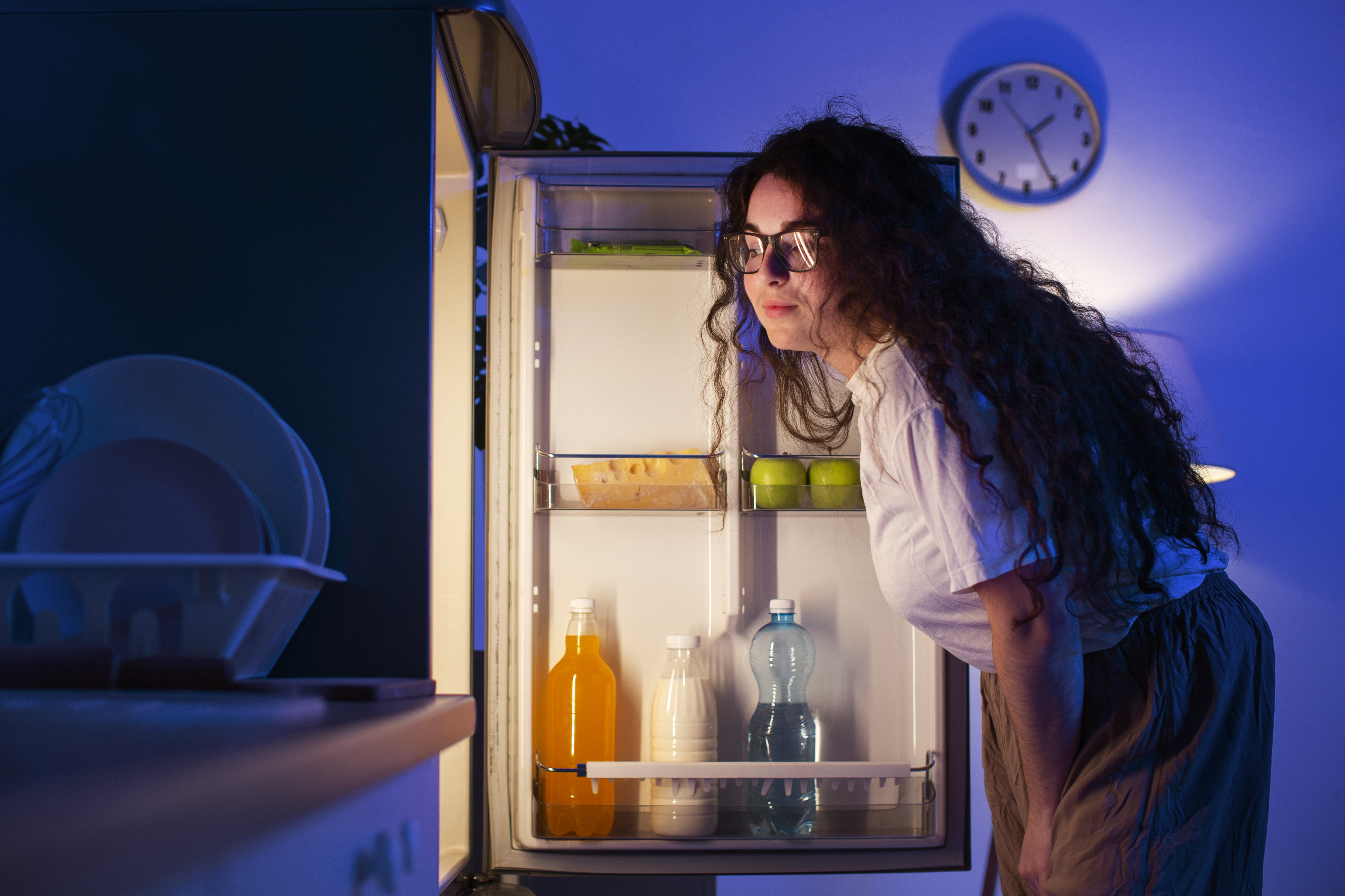 Joven frente a refrigeradora abierta mostrando un proceso termodinámico cotidiano