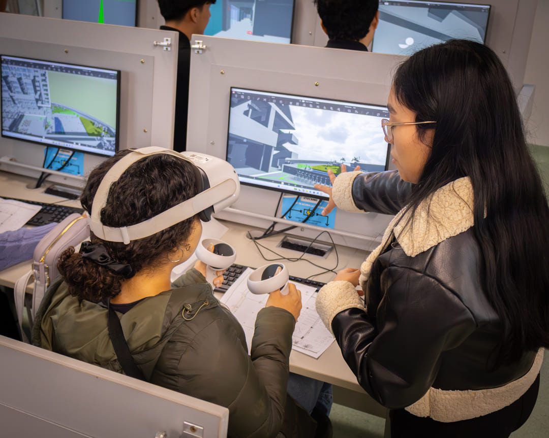 Una estudiante utiliza un visor de realidad virtual (VR) mientras otra explica el diseño en una pantalla, mostrando una tipología de la innovación aplicada al aprendizaje interactivo y arquitectura